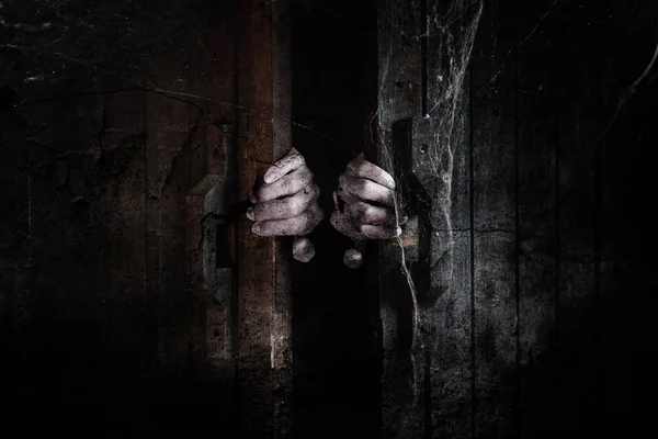Руки призрака открывают деревянную дверь изнутри старой темноты. — стоковое фото