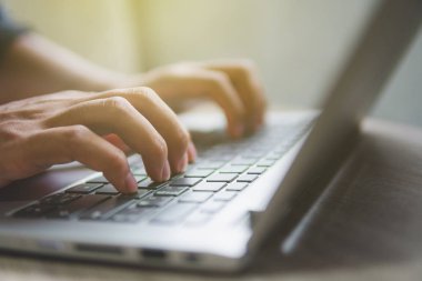 Evde dizüstü bilgisayar cıyla çalışarak blog yazıyor. Adam elleri üzerinde