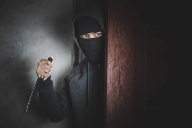 Hırsız soyguna karşı kapıyı açmak için bıçak tutuyor..