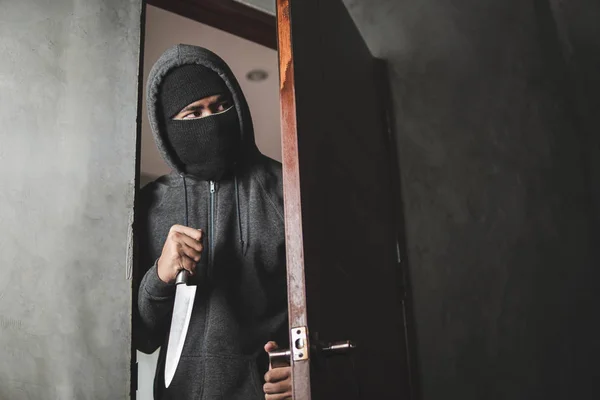 El ladrón sostiene un cuchillo para abrir la puerta de la casa por robo. — Foto de Stock