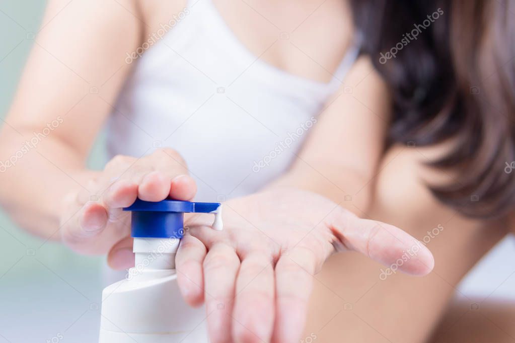 A beautiful Asian woman sitting on a bed pressing the cream Use 