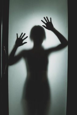 Mat camın arkasında bir kadının hayalet konsepti bulanık el ve vücut odaklanması