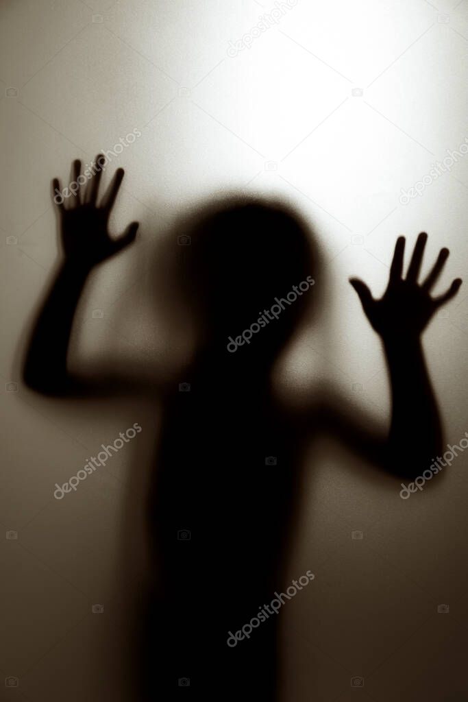 Ghost concept shadow of a child behind the matte glass blurry hand and body soft focus