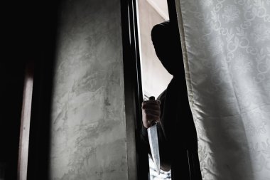 Hırsız, soyguna karşı kapıyı açmak için bıçak tutuyor. Bıçak suratını kimse görmemeli..