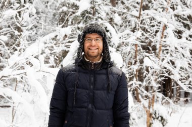 Kulağı olan kürk kış şapkalı adam gülümseyen portre flep. Ormanın içinde aşırı