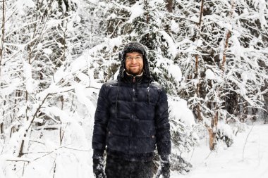 Kulağı olan kürk kış şapkalı adam gülümseyen portre flep. Ormanın içinde aşırı