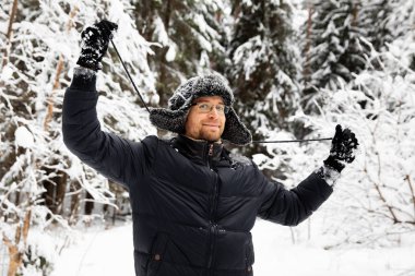 Kulağı olan kürk kış şapkalı adam gülümseyen portre flep. Ormanın içinde aşırı
