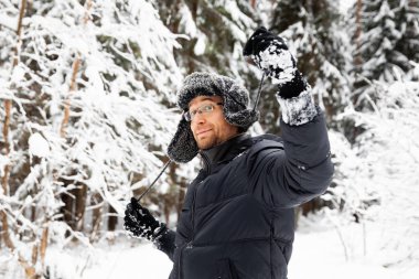 Kulağı olan kürk kış şapkalı adam gülümseyen portre flep. Ormanın içinde aşırı