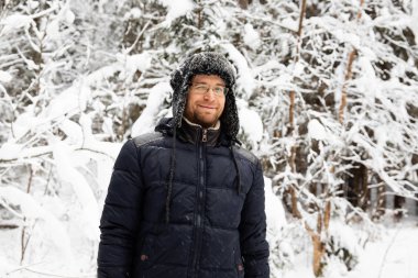 Kulağı olan kürk kış şapkalı adam gülümseyen portre flep. Ormanın içinde aşırı