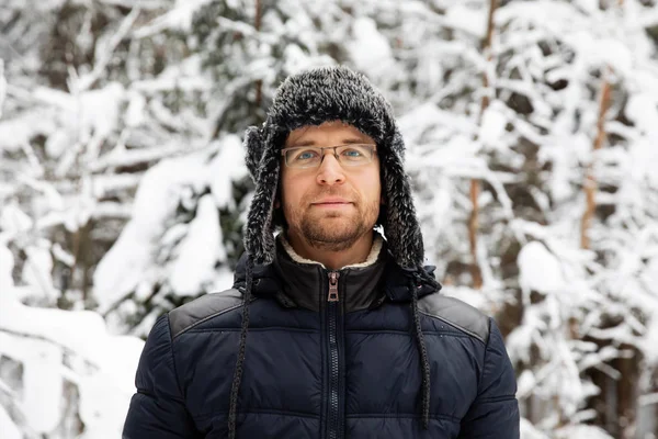 Kulağı olan kürk kış şapkalı adam gülümseyen portre flep. Ormanın içinde aşırı