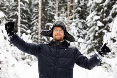 Kulağı olan kürk kış şapkalı adam gülümseyen portre flep. Ormanın içinde aşırı