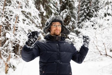 Kulağı olan kürk kış şapkalı adam gülümseyen portre flep. Ormanın içinde aşırı