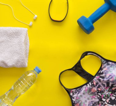 Lay, kadın spor top, su şişesi, halter, kalp oran sınıf başkanı, kulaklık, sarı arka plan, üstten görünüm, spor sutyeni havluda düz