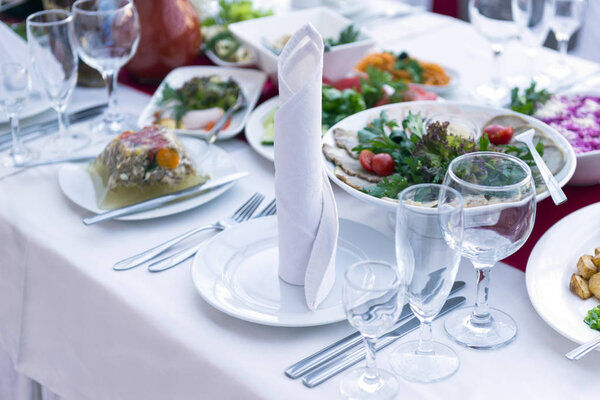 served table with snacks, dishes, glasses, food in plates, forks, knives, Cutlery, Banquet table