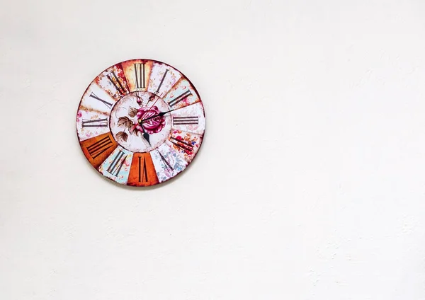 mechanical clock with a dial on a white wall, Roman numerals, clock hands, time, color clock, round clock