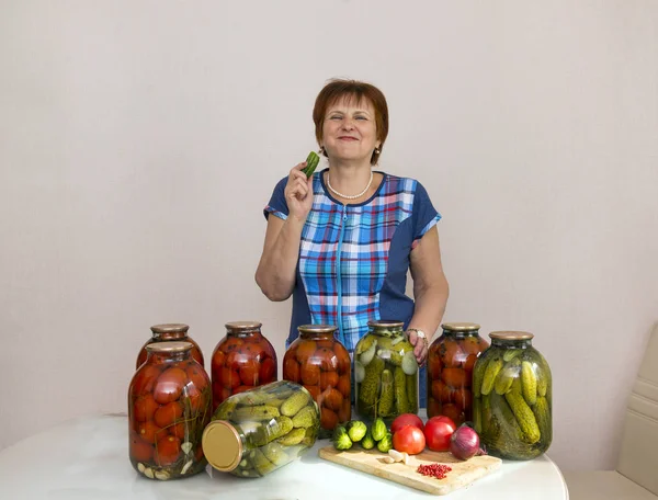 woman with canned pickles cucumbers and tomatoes, pickled vegetables, homemade food, white adult woman laughs , woman eats cucumber,
