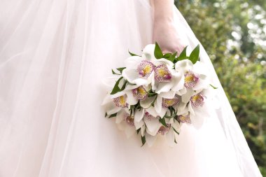 orkide arka planda bir beyaz gelinlik, çiçekler gelinin elinde buket düğün