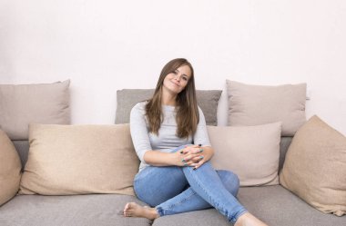 kanepede oturan ve gülümseyen 1 beyaz genç kadın