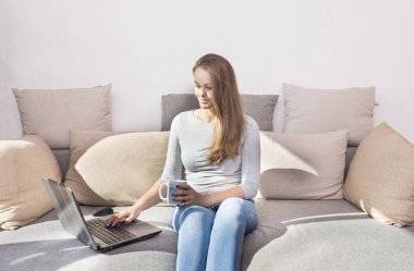  kanepe ve çalışma bilgisayar, bir kız bir kupa ve kanepeye, aracı bir kız gülümseyerek oturan beyaz kız