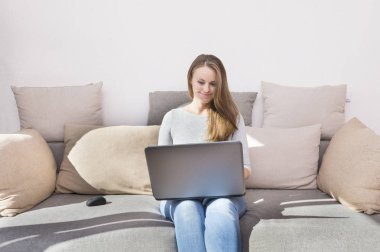 bir dizüstü bilgisayar, bir adam ve gadget, kanepenin üstünde oturan gülümsüyor, odasında bilgisayarda çalışan kız kız kot pantolon uzun saçlı 1 beyaz kız