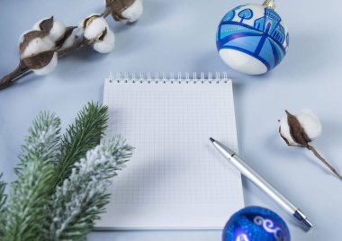 temiz beyaz Not Defteri sayfası, yazma, gümüş kolu, yeşil çam dalı, pamuk şube, mavi arka plan, üstten görünüm, üzerinde 2 mavi Noel topları için yer yakın çekim,