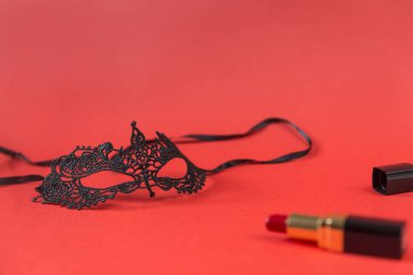 dantel siyah maskeli balo maskesi, kırmızı ruj kırmızı bir arka plan, Noel dekor üzerinde siyah bir durumda