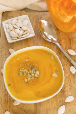bir tabak, kabak çekirdeği, kaşık, Taze kabak Ahşap Doğrama tahtası üzerinde bir parça balkabağı çorbası