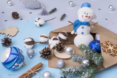 Ladin şube, pamuk şube, koniler, oyuncak kardan adam, zarf, Noel topları, mavi bir arka plan üzerinde kar tanesi gümüş