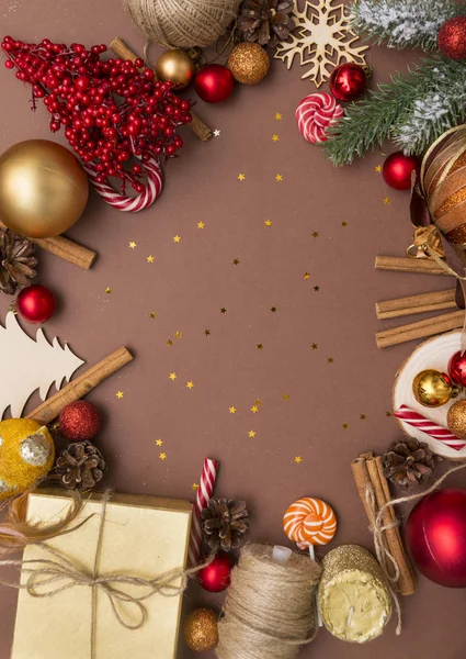 yazıt, Ladin şube, kırmızı ve altın Noel topları, koniler, tarçın, tatlı kahverengi bir arka plan üzerinde kırmızı meyveler, ip, yılbaşı ağacı, kar tanesi, altın kutu, hediye kutusu ile şube için yer, 