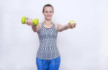holding bir dumbbell ve bir elma, bir kız mavi tozluk spor giysileri kızı