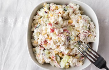 yengeç salata salatalık yumurta, beyaz masa örtüsü üzerinde beyaz bir tabak, çatal