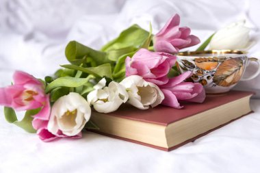 birkaç beyaz ve pembe laleler, kitap, çay kupa, beyaz sayfa