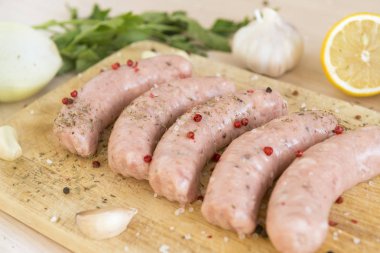 çiğ sosis, domuz sosisi üzerinde bir kesme tahtası, sarımsak, limon, baharatlar,