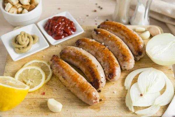 Kızarmış sosis, domuz sosisi hardal ketçap, soğan, limon kesme tahtası üzerinde