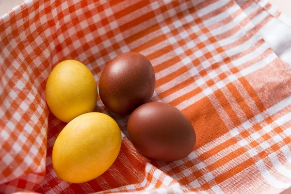 4 pisanki, żółte i brązowe jaja gotowane na ręcznik pomarańczowy — Zdjęcie stockowe