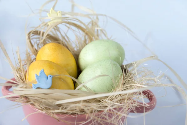 4 huevos en heno en un plato sobre fondo azul, amarillo y verde — Foto de Stock