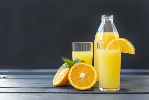 2 чашки апельсинового соку, пляшка соку, половина апельсина, гілочка м'яти — стокове фото