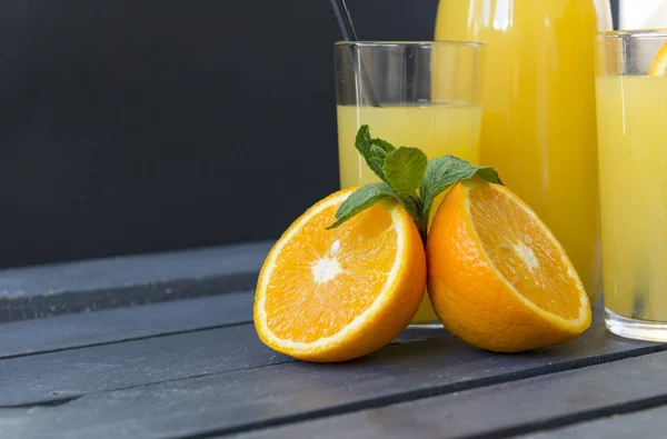 Наполовину апельсин з м'ятною гілочкою, склянкою апельсинового соку на дерев'яному спині — стокове фото