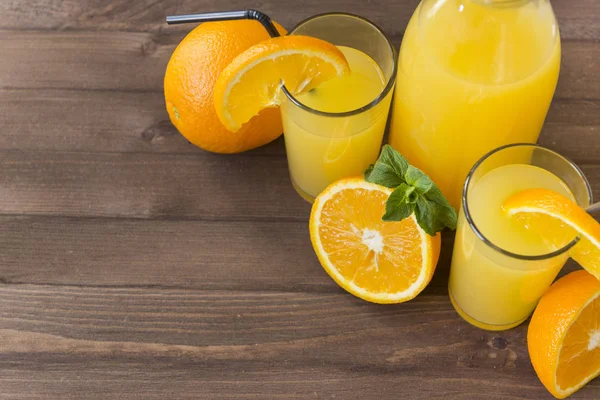 Апельсиновий сік склянка з м'ятою, пляшка соку на коричневій дерев'яній спині — стокове фото