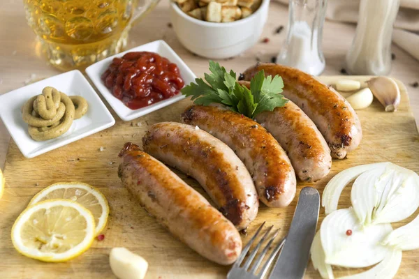 Fried meat sausages on cutting Board, ketchup, mustard, onion, g — Stock Photo, Image