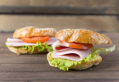 jambon, yaprak salata ve susam çörek üzerinde domates bir dilim