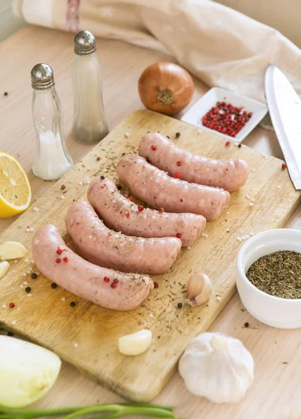 Salsichas de carne de porco crua com especiarias na tábua de corte — Fotografia de Stock