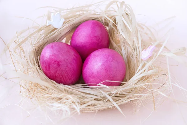 3 huevos de Pascua rosados en nido con heno sobre fondo beige, hervidos — Foto de Stock