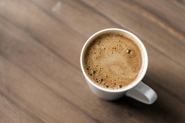 köpüklü bir kupa ahşap arka plan üzerinde siyah kahve