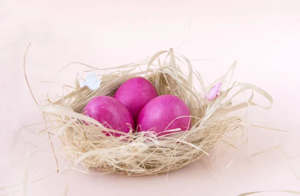Huevos de pollo pintados de Pascua rosados en el nido sobre fondo beige — Foto de Stock