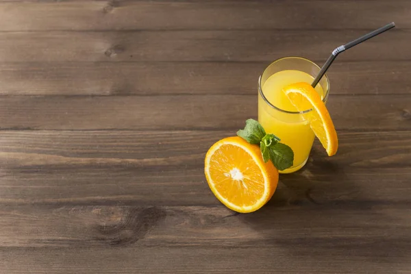 Стакан апельсинового сока с мятой, половина свежего апельсина, кусочек — стоковое фото