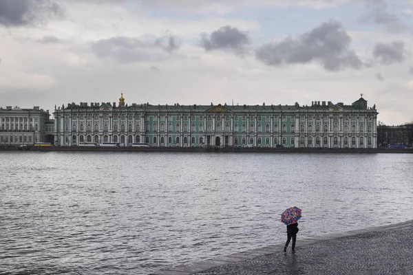 Vista del Palacio de invierno y el río Neva, un hombre bajo una miga — Foto de Stock