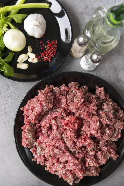 Carne moída crua em uma chapa preta, cebolas, alho, aipo, pimentão — Fotografia de Stock