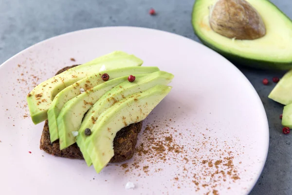 sliced avocado with spices on a piece of bread , half avocado on