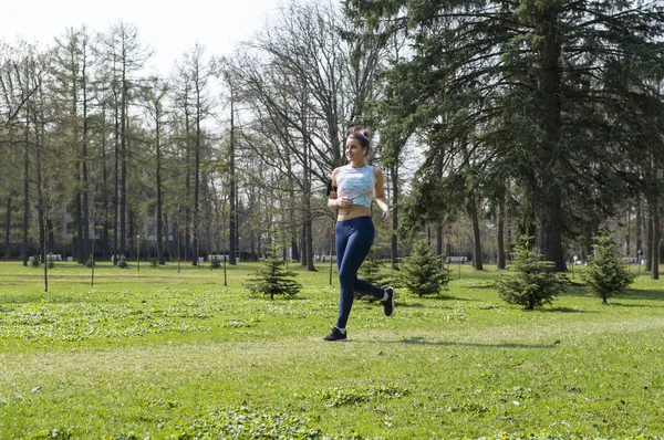 Menina esbelta correndo no parque entre a vegetação, corredor — Fotografia de Stock
